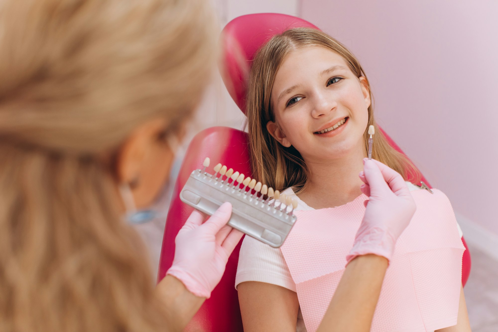 The dentist selects the color of the dental crown of a teenage girl in a dental clinic